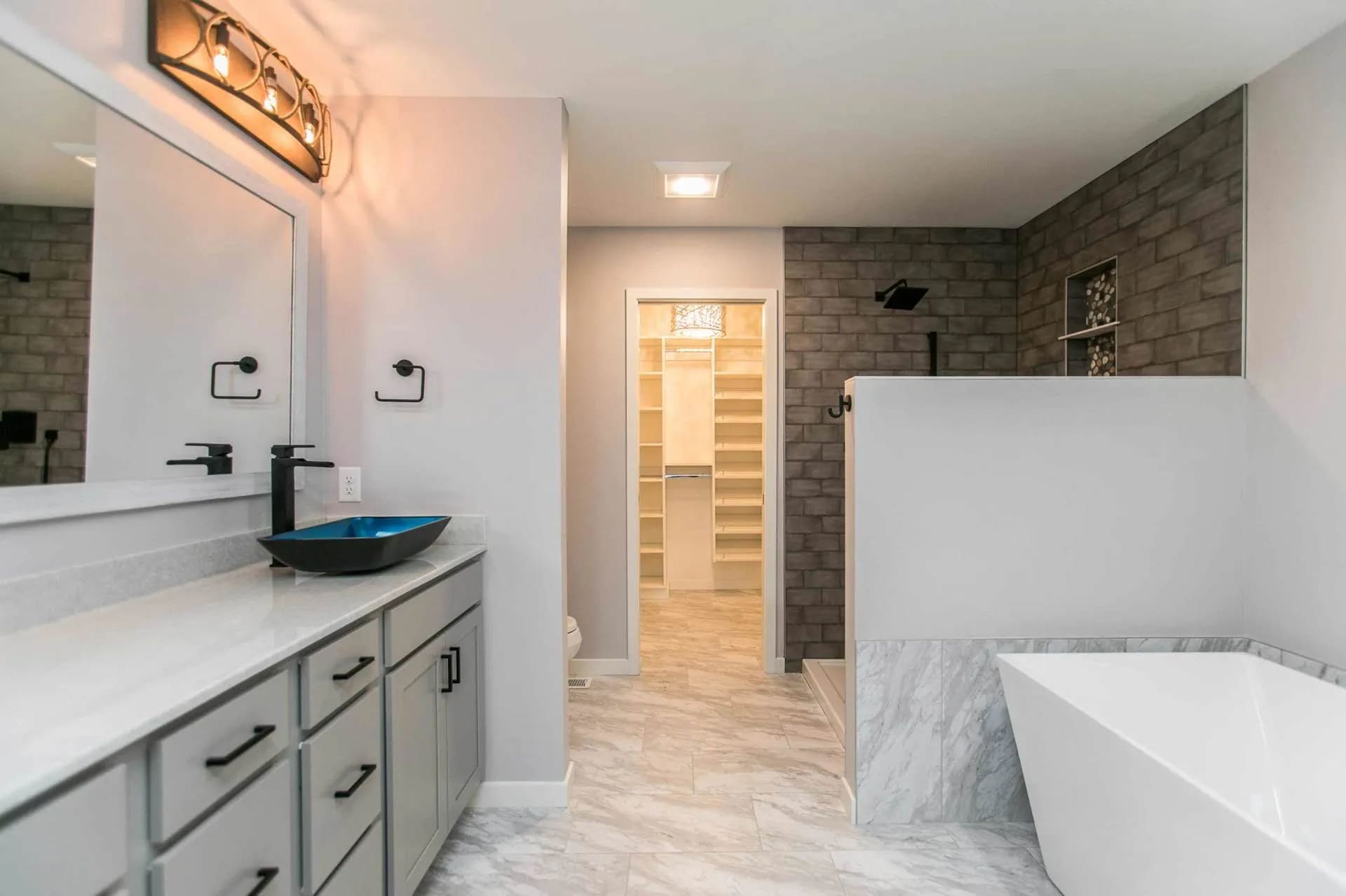 Primary bathroom with large soaker tub, custom tile shower, view of primary closet and large vanity with vessel bowl