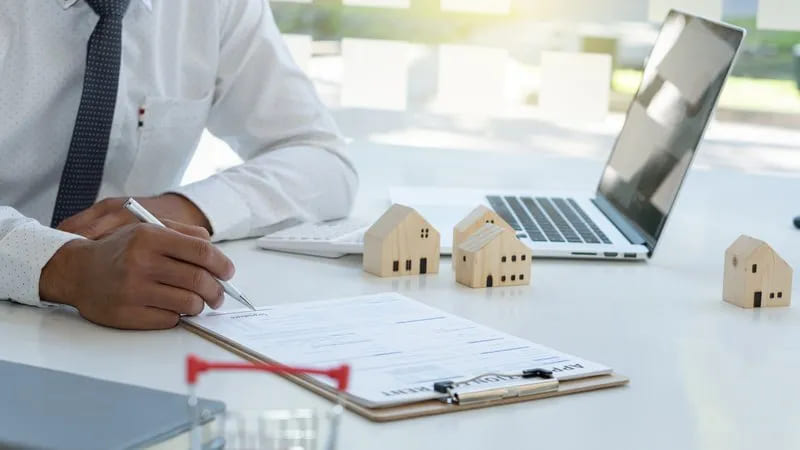 Man filling out application with toy houses around image