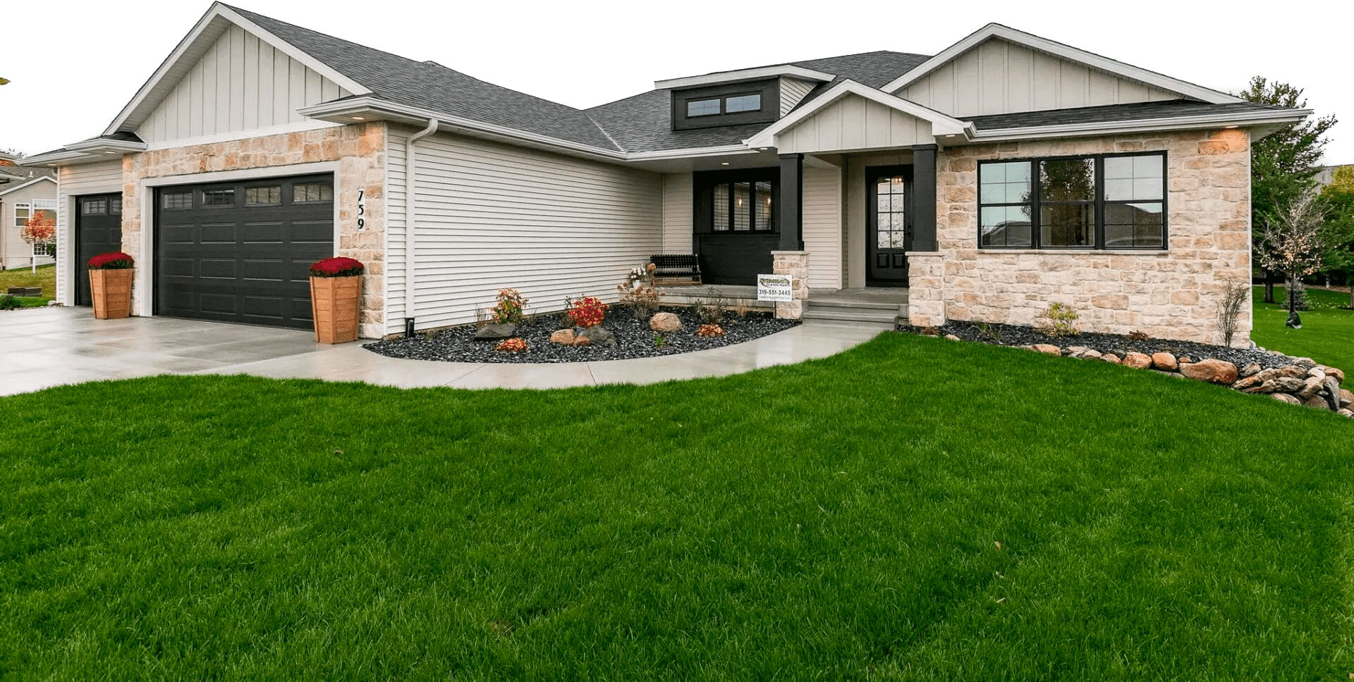 Exterior elevation of Stonegate Custom Homes Fall 2022 Parade home. LP Board and Batten gable accents, black LP trim details, Stone. Black windows. 8' tall front door.