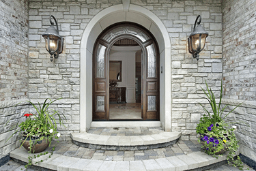Arched top front door surrounded by stone